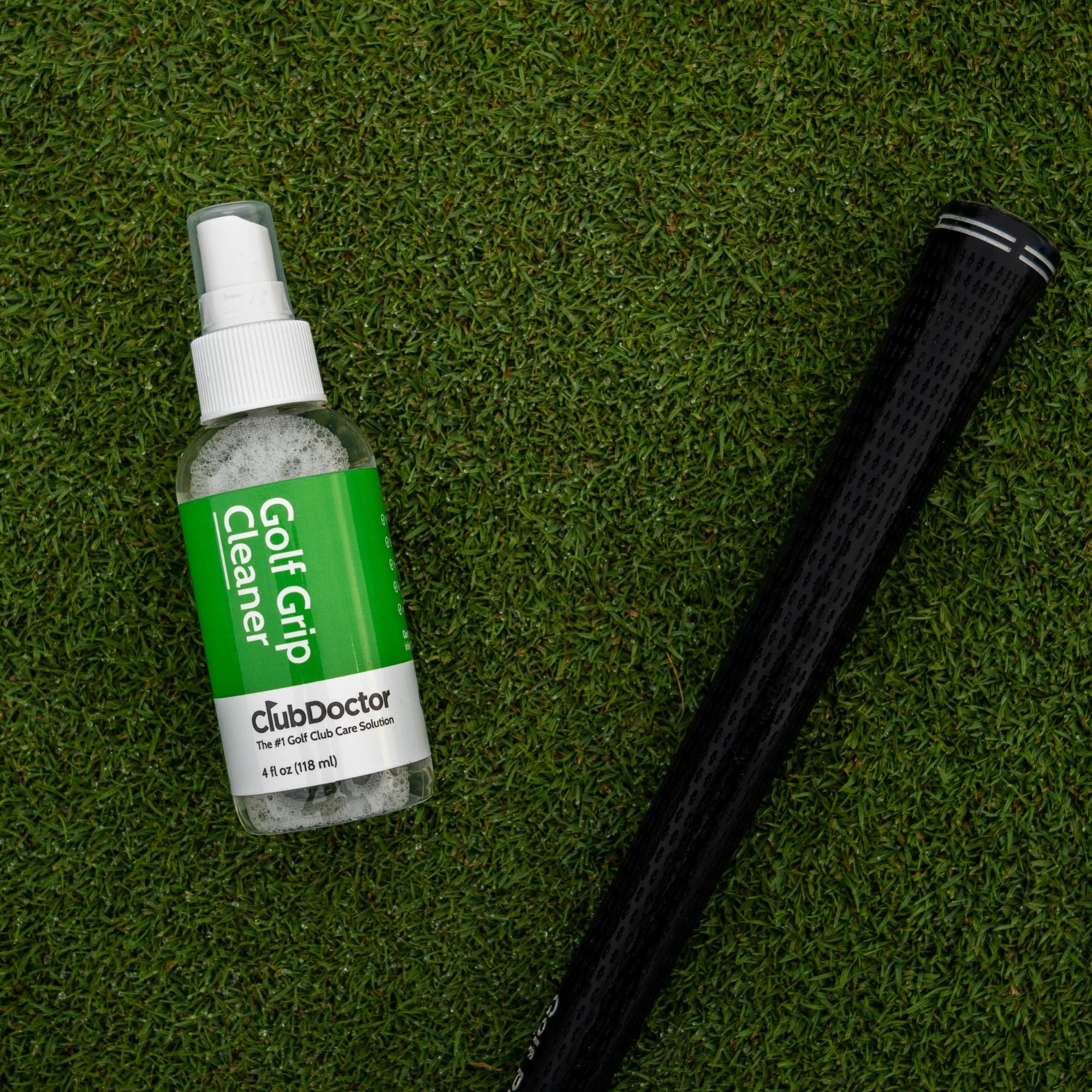 club doctor golf grip cleaner bottle laying on the ground next to a golf grip